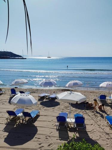 a beach with chairs and umbrellas and the ocean at Nikolas Marios by Frangki in Agia Marina Aegina