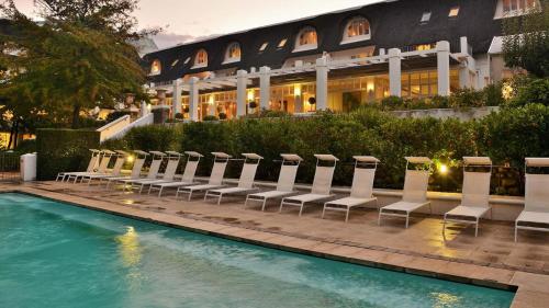 フランシュホークにあるLe Franschhoek Hotel & Spa by Dream Resortsの椅子付きのホテル、建物の前のプール