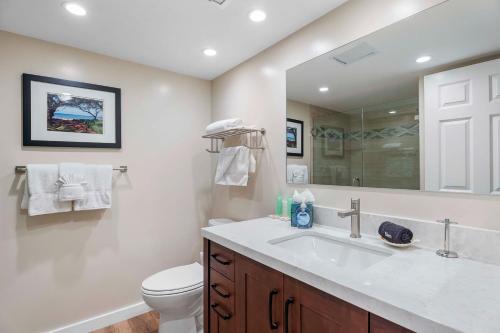 Un baño con lavabo, inodoro y espejo. en Kona Pacific D622, en Kailua-Kona