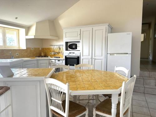 a kitchen with a table and chairs and a refrigerator at Les figuiers in La Londe-les-Maures