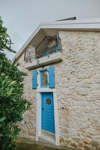 a building with a blue door and a balcony at Stone House Zrinski entire apartment 62 m2 in Luka