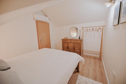a white bedroom with a bed and a mirror at Stone House Zrinski entire apartment 62 m2 in Luka