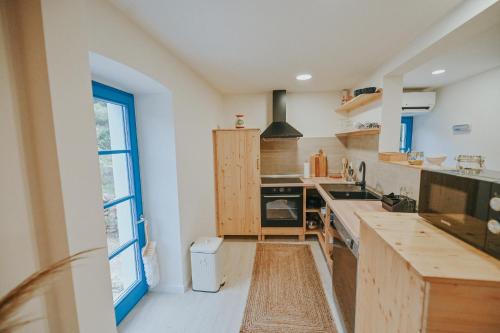 a kitchen with white walls and a large window at Stone House Zrinski entire apartment 62 m2 in Luka