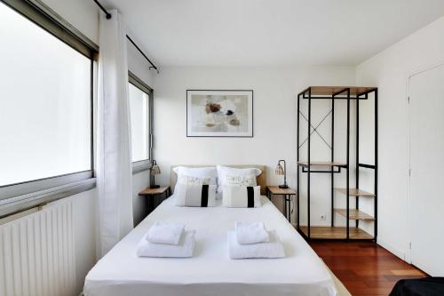 une chambre avec un grand lit avec des draps et des oreillers blancs dans l'établissement Stunning studio - 2P - La Vilette, à Paris