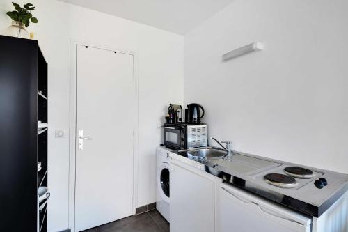 une cuisine blanche avec un évier et une machine à laver dans l'établissement Stunning studio - 2P - La Vilette, à Paris
