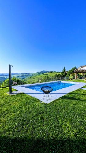a swimming pool with a table in the grass at Villa Perla, hilltop location with pool in Calosso
