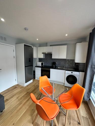 a kitchen with a glass table and two orange chairs at Maple Street Apartments in London
