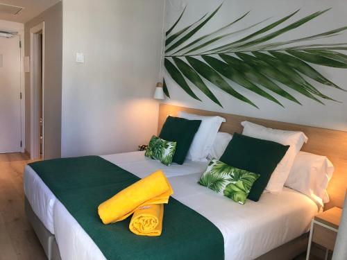 a bedroom with a bed with green and yellow pillows at BQ Paguera Boutique Hotel - Adults Only in Paguera