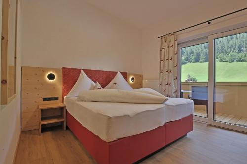 a bedroom with a large bed and a large window at Bergsporthotel Antonie in Gries im Sellrain