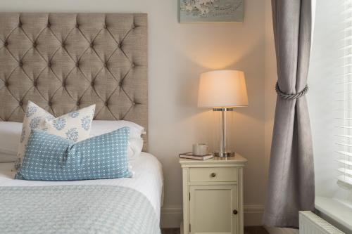 a bedroom with a bed with a blue pillow and a lamp at The Old Quay House Hotel in Fowey