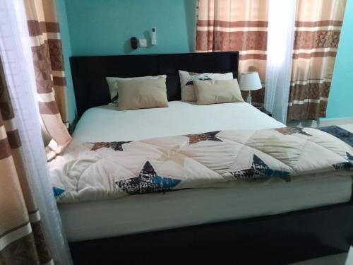 a bed with a white comforter and pillows at Matata Homes Airbnb in Kasoa