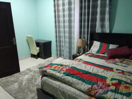 a bedroom with a bed and a desk and a chair at Matata Homes Airbnb in Kasoa