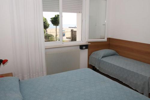 a room with two beds and a window at Villa Mazzon Family Apartments in Lido di Jesolo