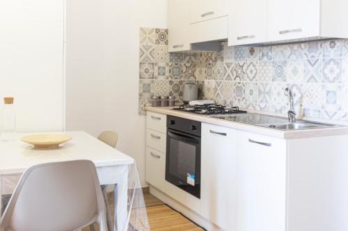 a white kitchen with a sink and a stove at Serra Cozy Apartments in Centola