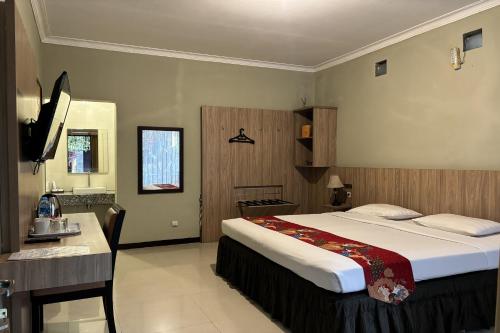 a bedroom with a bed and a desk and a sink at Hotel Pesona Bamboe Lembang in Genteng