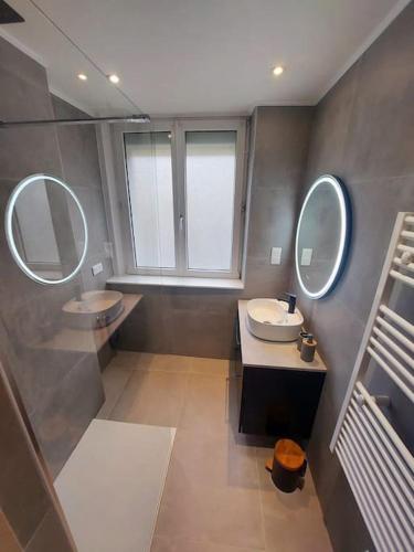 une salle de bain avec deux lavabos et deux miroirs dans l'établissement Appartement 3 ch avec garage, proche Techn'hom, à Belfort