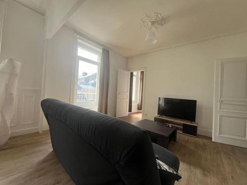 un salon avec un canapé et une télévision dans l'établissement L'Entracte Cherbourgeois, à Cherbourg en Cotentin