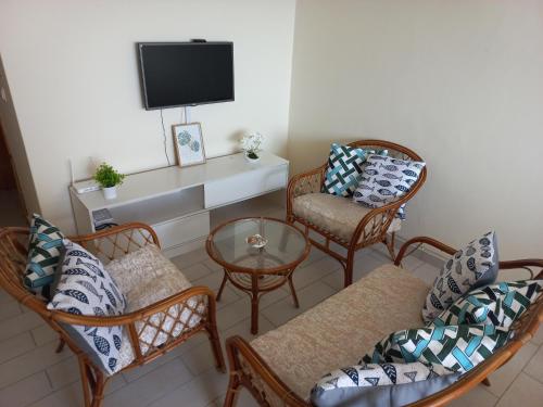 a living room with wicker chairs and a tv at Brisa e Paz in Praia