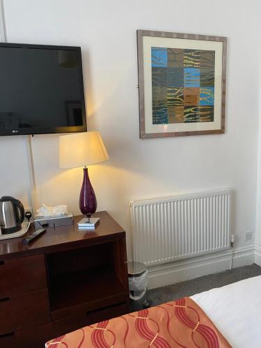 a hotel room with a bed and a desk with a tv at The Bailey Hotel Blackpool in Blackpool