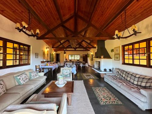 un grand salon avec des canapés et une cheminée dans l'établissement Pousada da Trilha, à Monte Verde