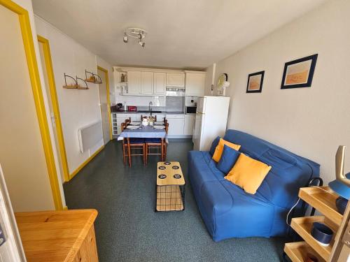 un salon avec un canapé bleu et une cuisine dans l'établissement Appartement FACE A LA MER Rez de jardin avec Cour Proche du Lydia, au Barcarès