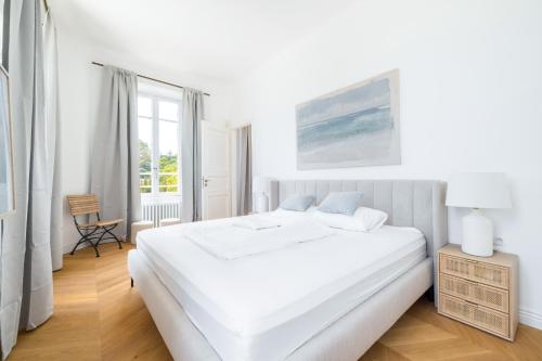 une chambre blanche avec un grand lit et une chaise dans l'établissement Villa Marli, à Antibes