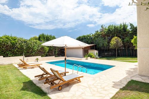 une piscine avec deux chaises et un parasol dans l'établissement Villa Marli, à Antibes