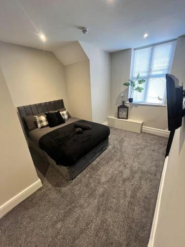 a bedroom with a black bed and a window at Stunning 2 Bedroom Ground Floor Sea View Apartment in Llandrillo-yn-Rhôs