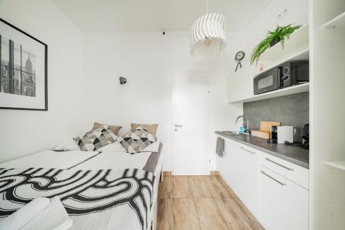 a white bedroom with a bed and a kitchen at City Center Lofts in Vienna