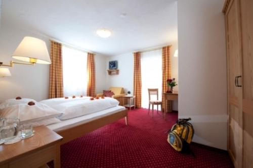 a hotel room with a large bed and a desk at Hotel Oberwirt in Feldthurns