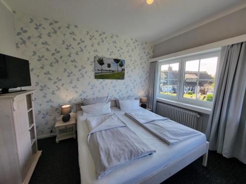 a bedroom with a white bed and a television at Hotel Schleimünde in Kappeln