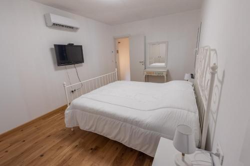 a white bedroom with a bed and a tv at La Casetta in Comacchio