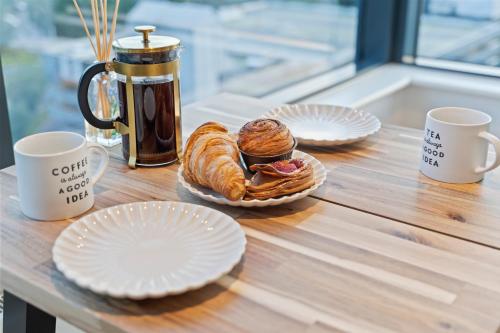a table with plates of pastries and coffee cups at Heathrow Retail Park Apartment Sleeps SEVEN Turbo WiFi in Sunbury Common