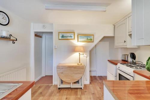 eine Küche mit weißen Schränken und einem Tisch mit einer Lampe in der Unterkunft Fisherman's Cottage in Hastings Old Town in Hastings