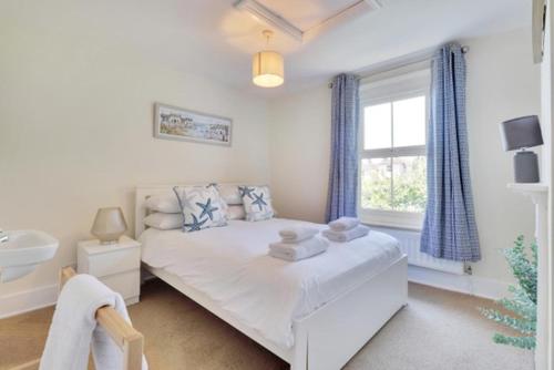 ein weißes Schlafzimmer mit einem Bett und einem Fenster in der Unterkunft Fisherman's Cottage in Hastings Old Town in Hastings