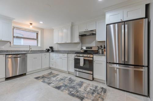 a kitchen with white cabinets and a stainless steel refrigerator at Entire Apt Near Wharf in Boston