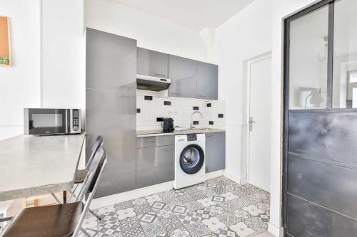 une cuisine avec une machine à laver et une table avec des chaises dans l'établissement Bright appt - Bibliothèque François Mitterrand, à Paris