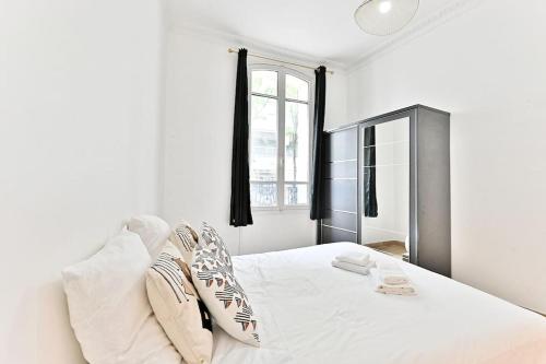 une chambre blanche avec un grand lit blanc avec des oreillers dans l'établissement Appartement 2 chambres Pyrénées Alexandre Dumas-II, à Paris