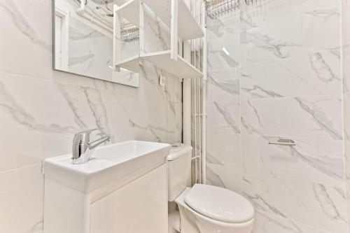 une salle de bain blanche avec des toilettes et un lavabo dans l'établissement Appartement 2 chambres Pyrénées Alexandre Dumas-II, à Paris