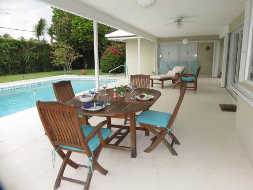 a wooden table and chairs next to a swimming pool at Spacious villa, pool, water views, walk to beach in West Palm Beach