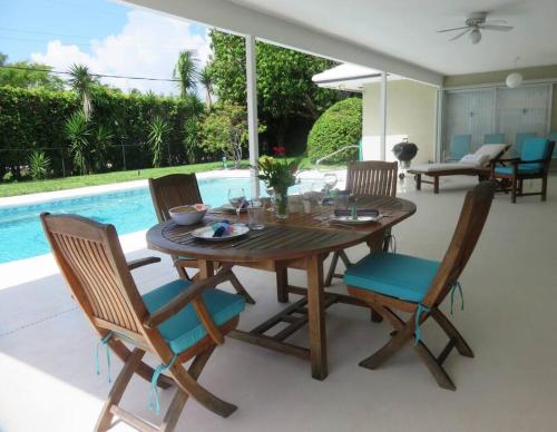 a wooden table and chairs on a patio with a pool at Spacious villa, pool, water views, walk to beach in West Palm Beach
