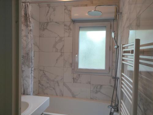 une salle de bain avec une baignoire, un lavabo et une fenêtre dans l'établissement T2 Toulouse Sud, à Toulouse