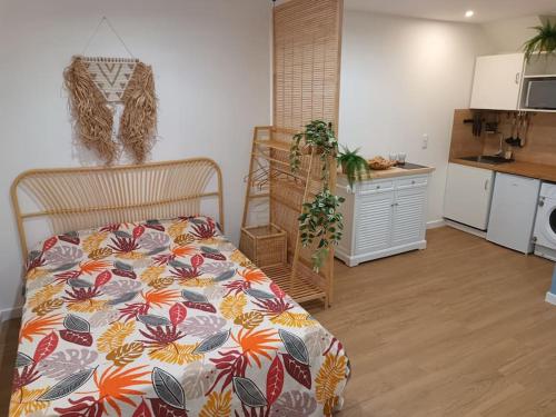 une chambre avec un lit avec une couette fleurie et une cuisine dans l'établissement Charmant studio centre-ville Montpellier, à Montpellier