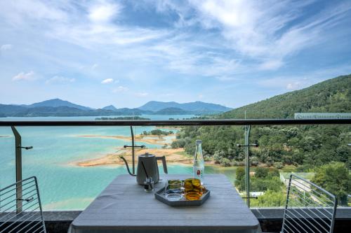 a table on a balcony with a view of the water at Huangshan Taiping Lake Muxin Hotel in Fenghuangshan