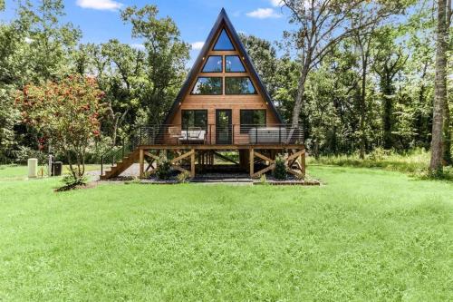 a cabin in the woods with a green lawn at Willow A-Frame in New Iberia