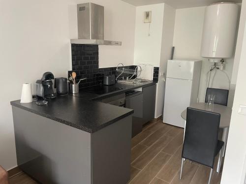 Il comprend une cuisine équipée d'un comptoir noir et d'un réfrigérateur. dans l'établissement Charmant deux pièces avec balcon, à Saint-Denis