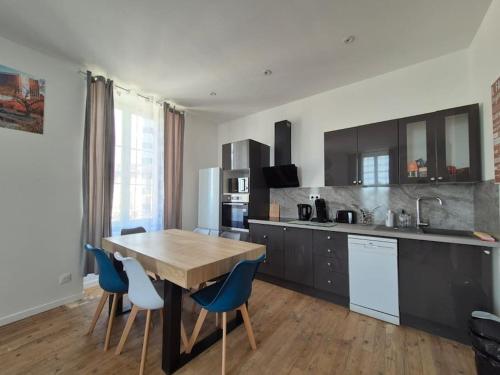 une cuisine avec une table en bois et des chaises bleues dans l'établissement #L'Entracte# Thiers# Centre#, à Thiers