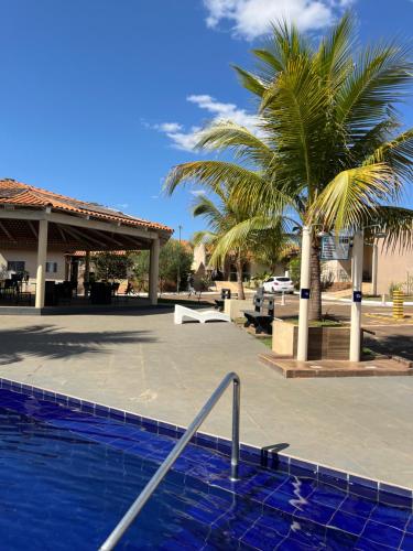 a palm tree and a swimming pool in a parking lot at Casa da Mari in Caldas Novas