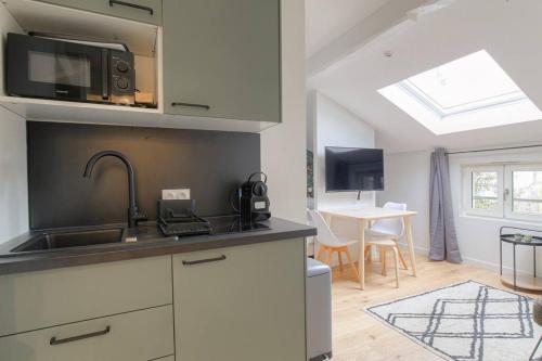 une cuisine avec un évier et un plan de travail dans l'établissement Appartement neuf, clim et parking, Caluire-Cité Intl, à Caluire-et-Cuire