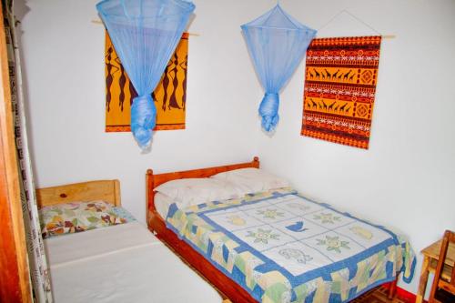 a bedroom with two beds and blue curtains on the wall at Hostel Pensão Ya Mute in Chimoio